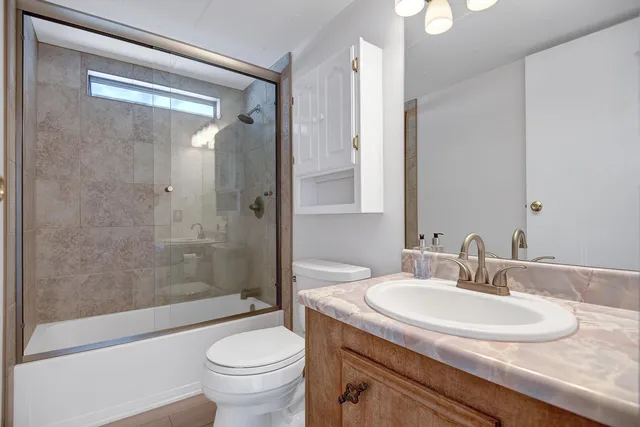 a bathroom with a granite countertop sink a toilet and shower