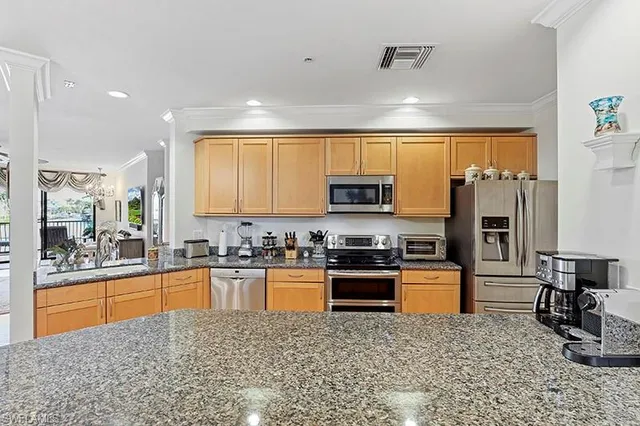 a large kitchen with stainless steel appliances granite countertop a stove top oven a sink a dining table and chairs