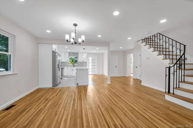 a view of a room with wooden floor staircase and a kitchen