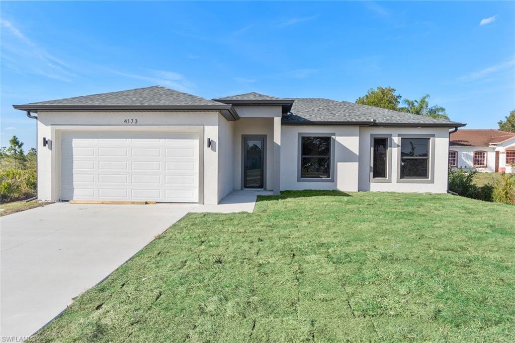 Prairie-style house featuring an attached garage, driveway, a front yard, and stucco siding