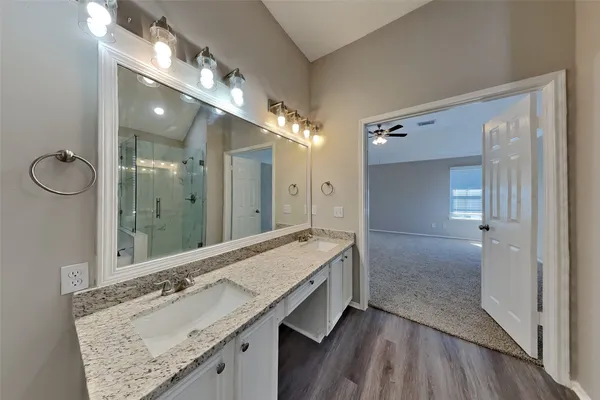 a bathroom with a granite countertop sink a large mirror and a shower