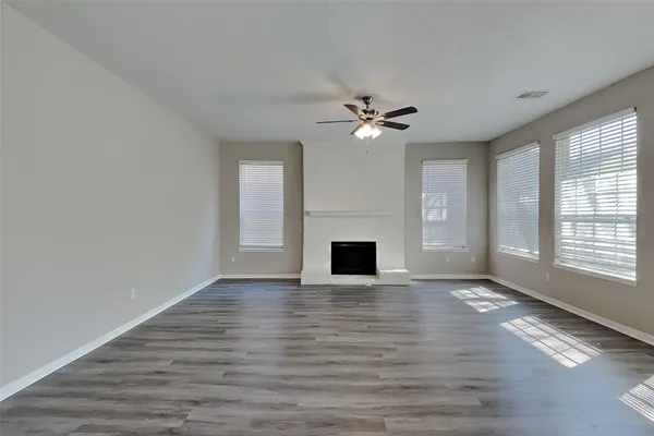 an empty room with windows fireplace and a sink