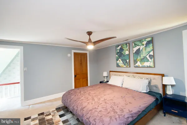 a bedroom with a bed and dresser with wooden floor