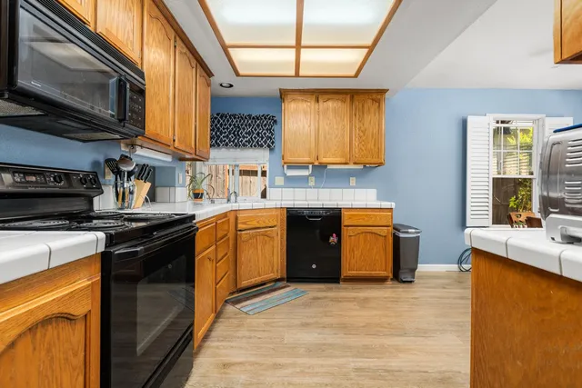 a kitchen with stainless steel appliances granite countertop a sink a stove top oven a chimney cabinets and a dining table