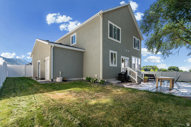 2706 West Maple Street, Unit 285 Mapleton, UT 84664 - Photo 31 of 36 Rear exterior featuring a stamped concrete patio, white vinyl fencing, and a grassy yard
