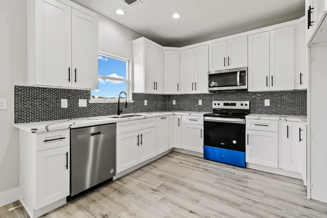 a kitchen with cabinets stainless steel appliances a sink and a stove
