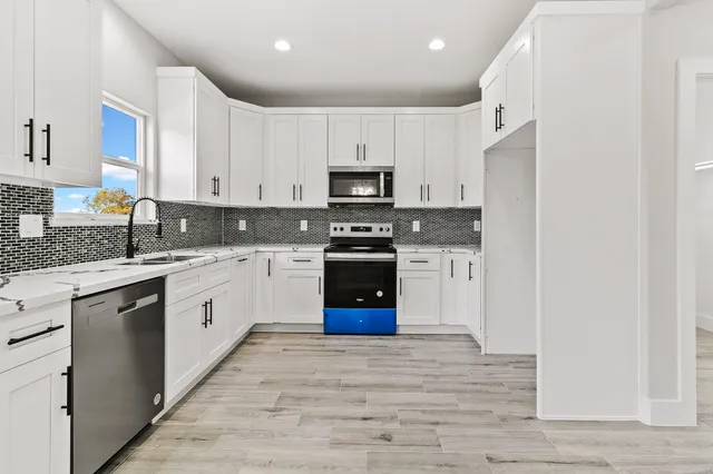 a view of a kitchen with a stove wooden floor a chandelier and wooden floor