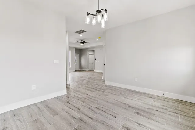 an empty room with wooden floor ceiling fan and windows