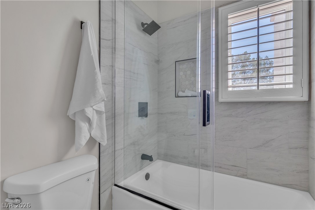 8848 Rainbow Ridge Drive Las Vegas, NV 89117 - Photo 22 of 43 A well-appointed bathroom features a bathtub with a sleek glass enclosure and a window for natural light.