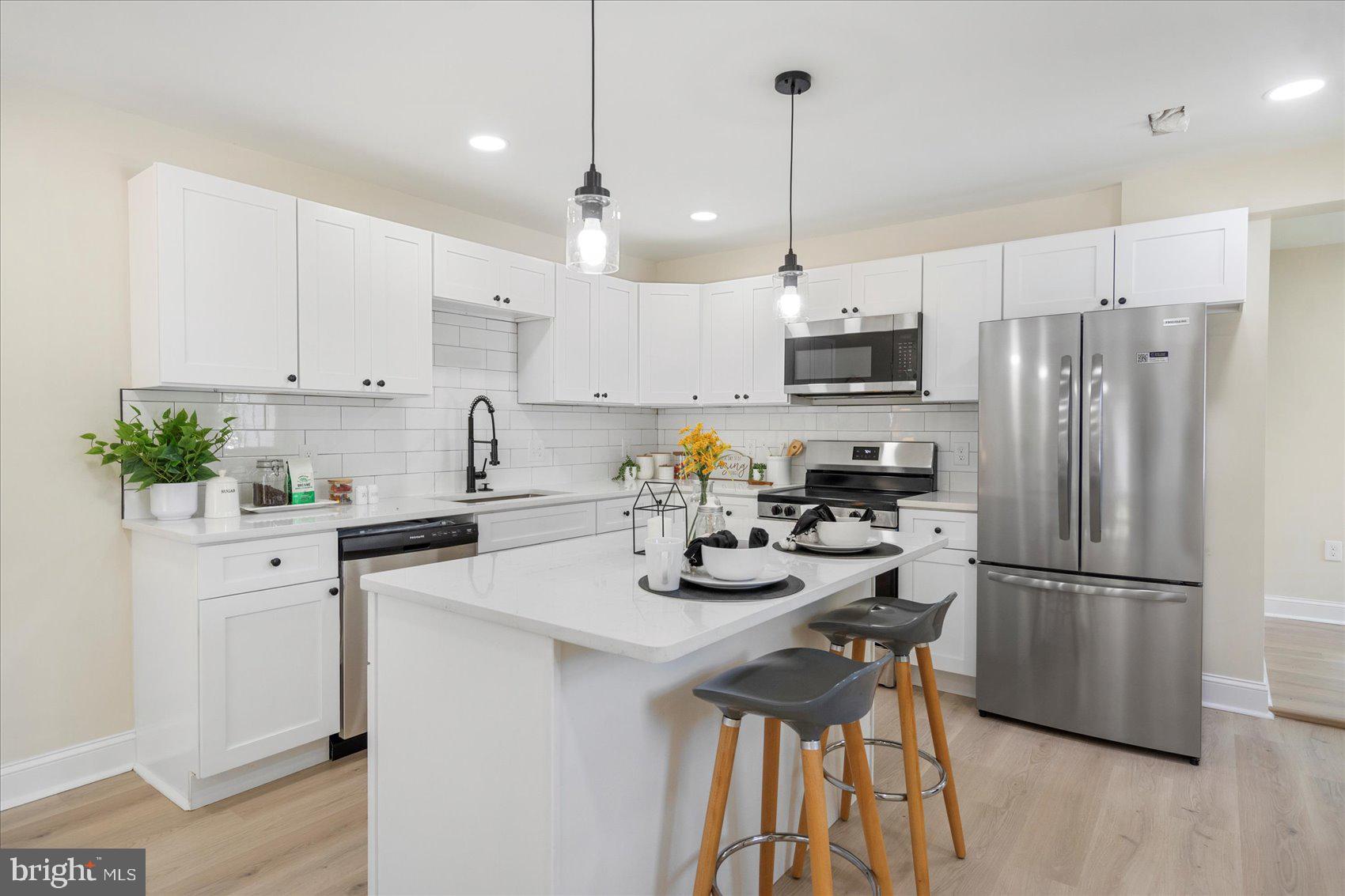 8111 Holly Road Curtis Bay, MD 21226 - Photo 12 of 46 a kitchen with stainless steel appliances granite countertop a refrigerator a sink dishwasher a stove and white cabinets with wooden floor