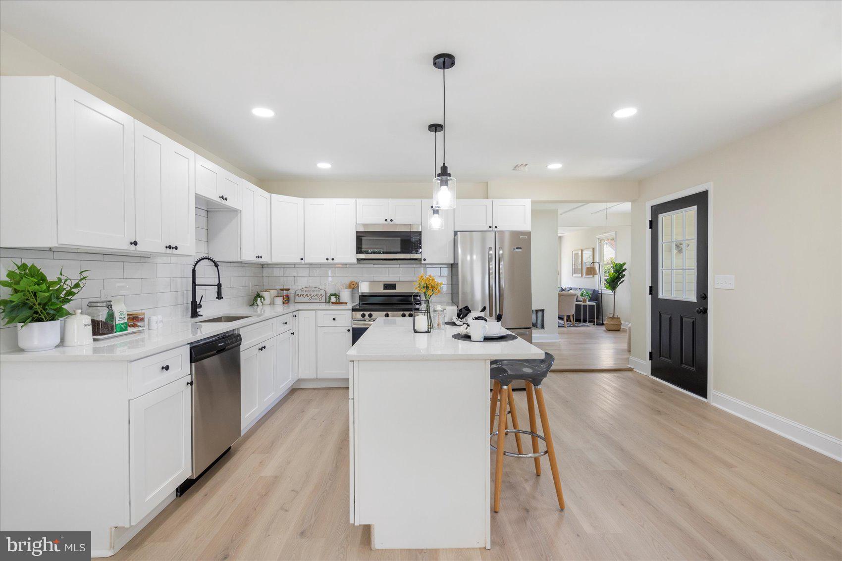 8111 Holly Road Curtis Bay, MD 21226 - Photo 13 of 46 a kitchen with kitchen island a white counter top space a sink cabinets and stainless steel appliances