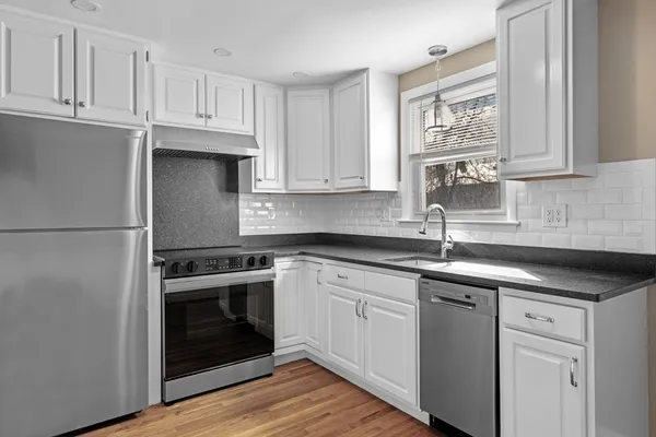 a kitchen with cabinets stainless steel appliances a sink and wooden floor