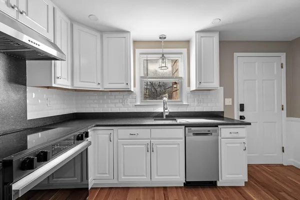a kitchen with granite countertop white cabinets and a sink