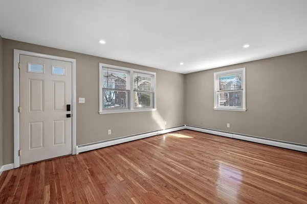 a view of an empty room with window and wooden floor