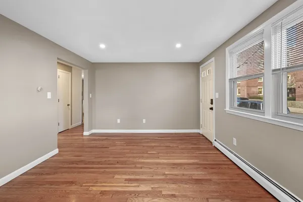 a view of an empty room with wooden floor and a window