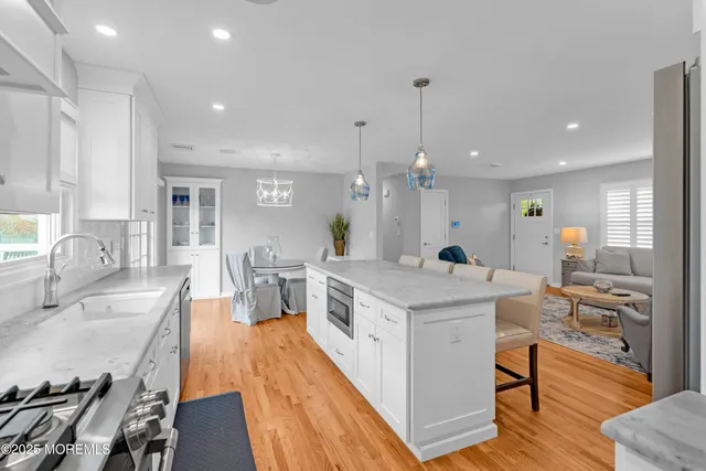 a large kitchen with stainless steel appliances a stove center island a large window and chairs