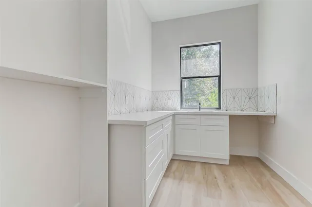 a kitchen with white cabinets and window