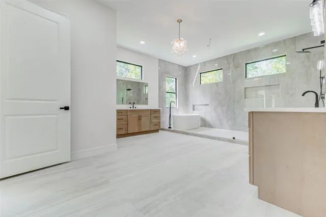 a spacious bathroom with double vanity sink a two mirror a window and a bathtub