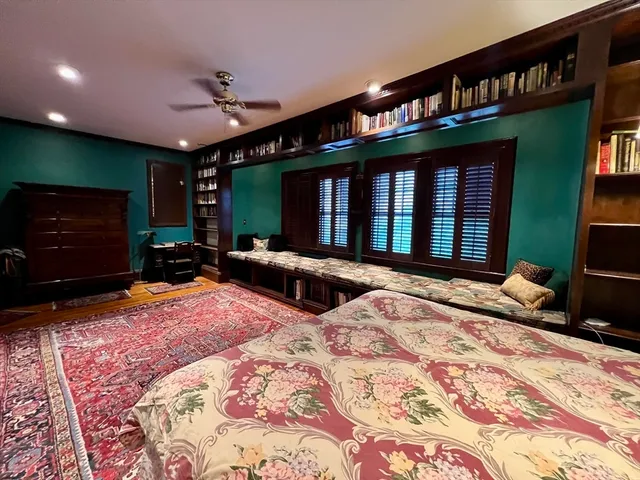 a bedroom with a bed a large window and potted plant on a table