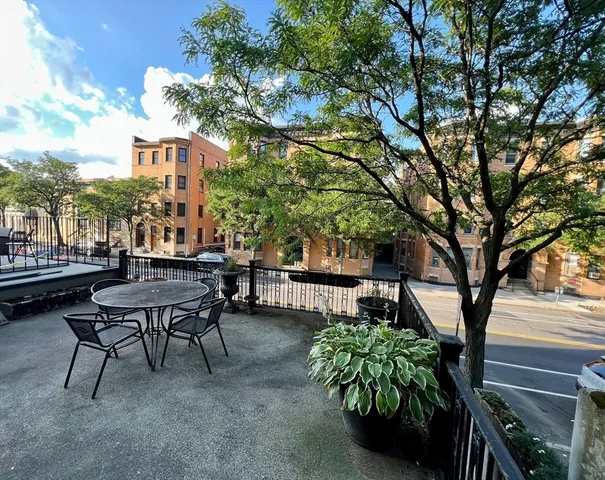 a view of a patio with table and chairs and a large tree