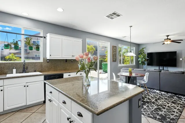 a kitchen with stainless steel appliances granite countertop a refrigerator a stove a sink dishwasher and white cabinets with wooden floor