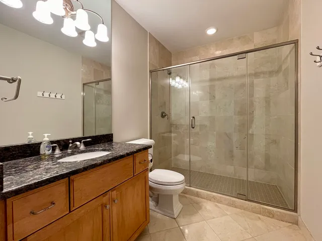 a bathroom with a granite countertop sink a toilet a mirror and shower