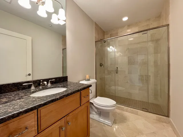 a bathroom with a granite countertop sink a toilet and shower