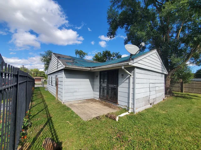 a backyard of a house with plants and barbeque oven