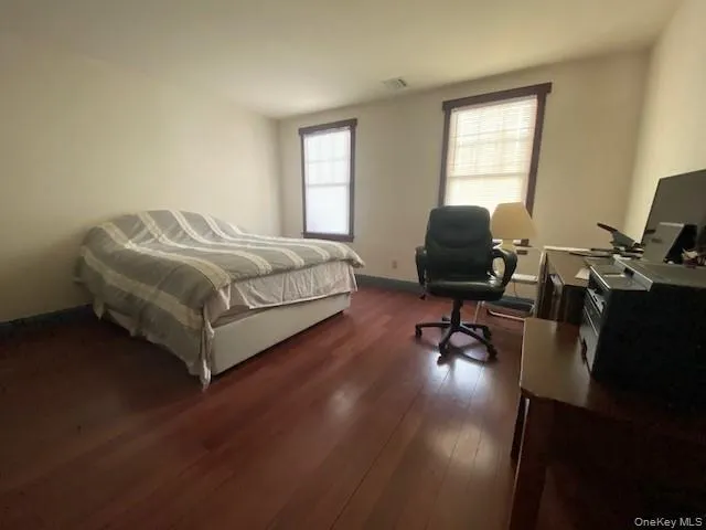a bedroom with a bed a desk chair and windows