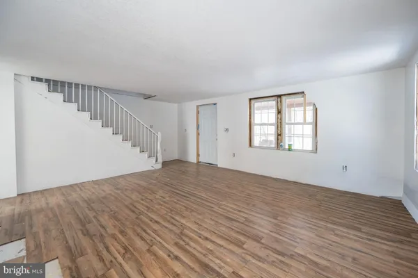 a view of an empty room with wooden floor and stairs