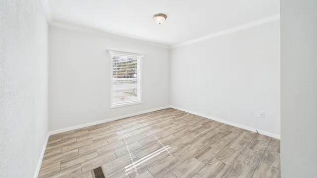 a view of empty room with wooden floor and fan