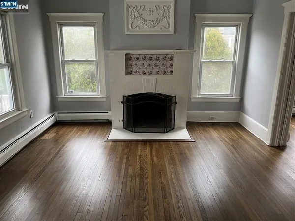 an empty room with wooden floor a fireplace and windows