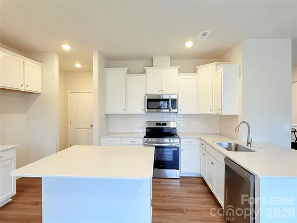 a large kitchen with stainless steel appliances kitchen island granite countertop a sink and cabinets