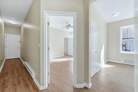 a view of hallway with bathroom and wooden floor