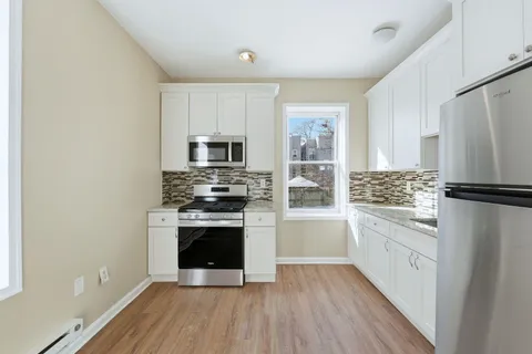 a kitchen with white cabinets and stainless steel appliances