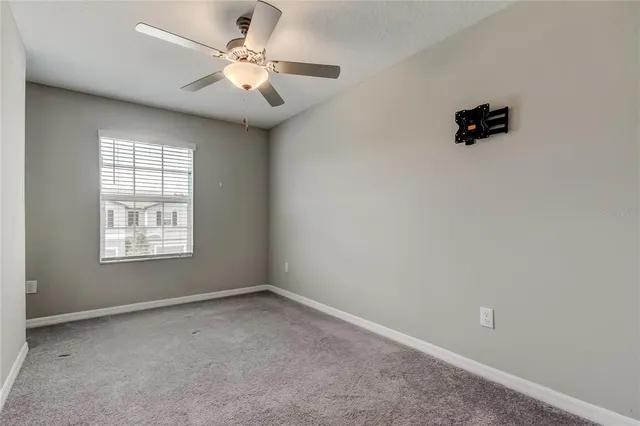 an empty room with a chandelier fan and windows