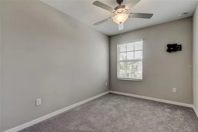 an empty room with a ceiling fan and a window
