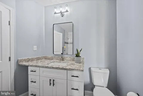 a bathroom with a granite countertop toilet sink and mirror