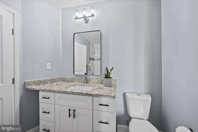 a bathroom with a granite countertop toilet sink and mirror