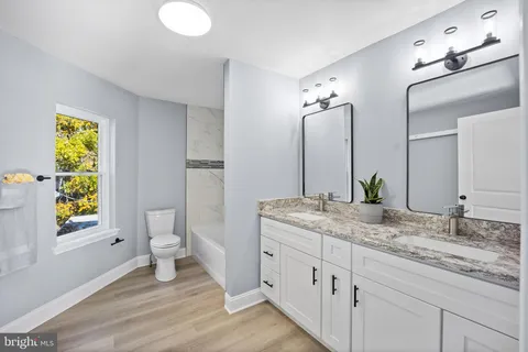 a bathroom with a granite countertop sink toilet and mirror