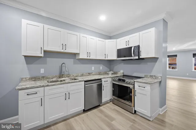 a kitchen with stainless steel appliances granite countertop a stove a sink and white cabinets