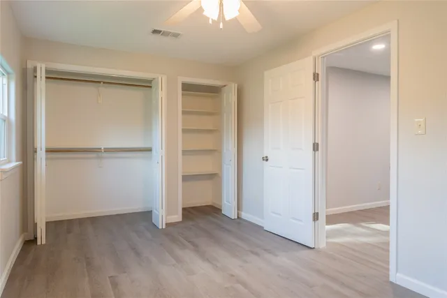 an empty room with wooden floor closet and windows