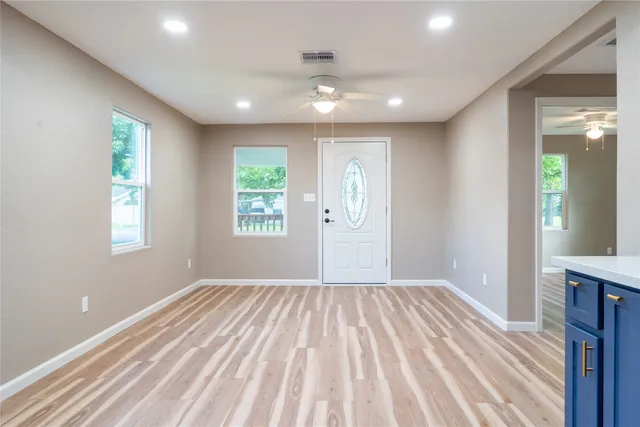 a view of empty room with wooden floor and fan