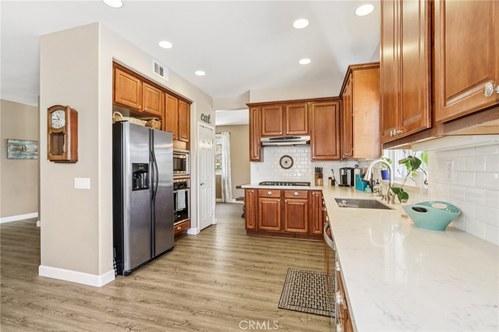 19941 Christopher Lane Saugus, CA 91350 - Photo 19 of 34 a kitchen with stainless steel appliances granite countertop a refrigerator a stove top oven and a sink with wooden floor