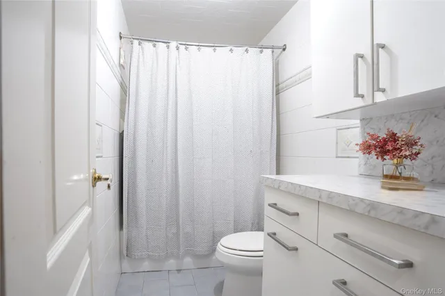 a bathroom with a granite countertop sink a toilet and a shower