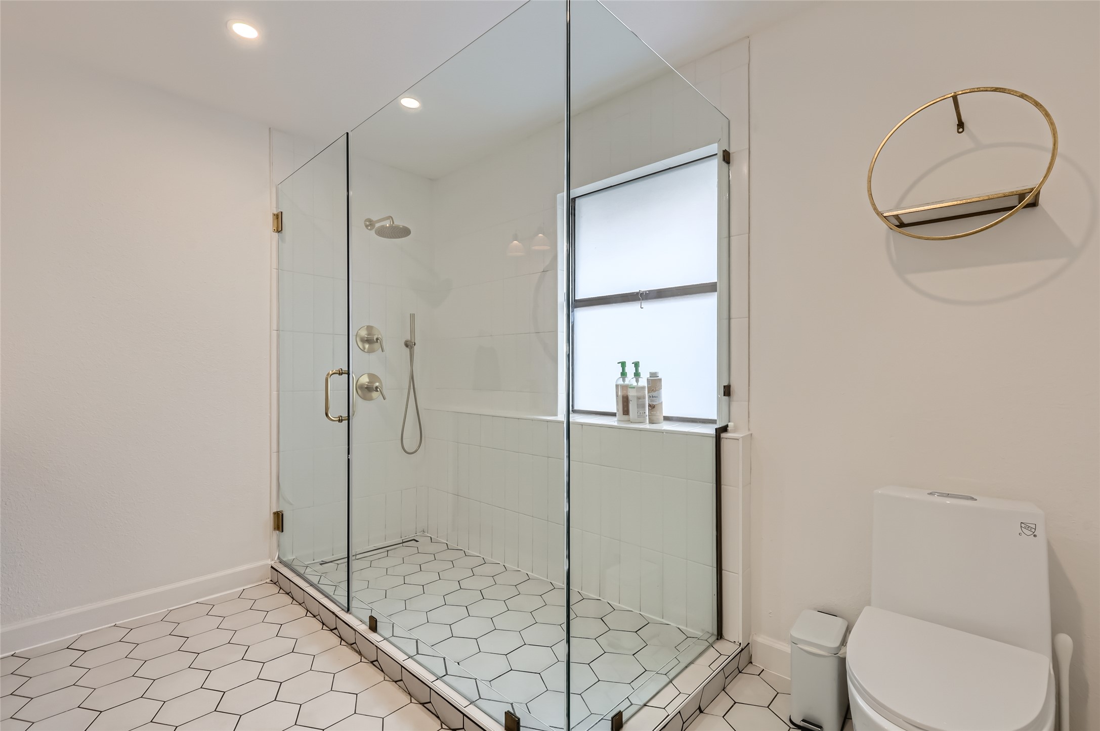 13205 Kepler Cove Austin, TX 78729 - Photo 19 of 34 Spacious walk-in shower with a frameless glass enclosure, rainfall showerhead, and white hexagonal floor tiling