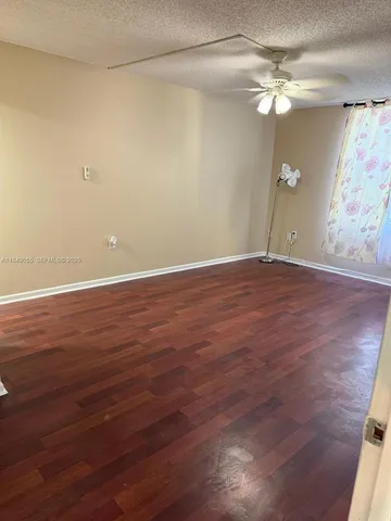 an empty room with wooden floor fan and window
