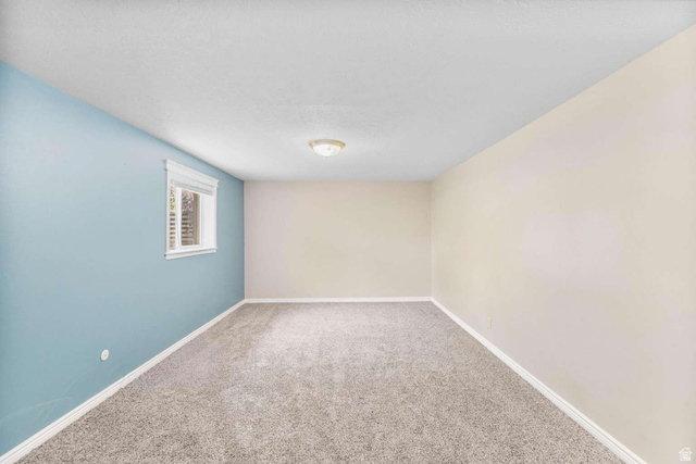 415 East 1150th Street North Logan, UT 84341 - Photo 20 of 38 Room featuring light blue and off-white painted walls, textured ceiling, a flush mount ceiling light fixture, a window with blinds, and grey-flecked carpeting