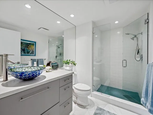a spacious bathroom with a granite countertop sink a toilet a shower and a mirror
