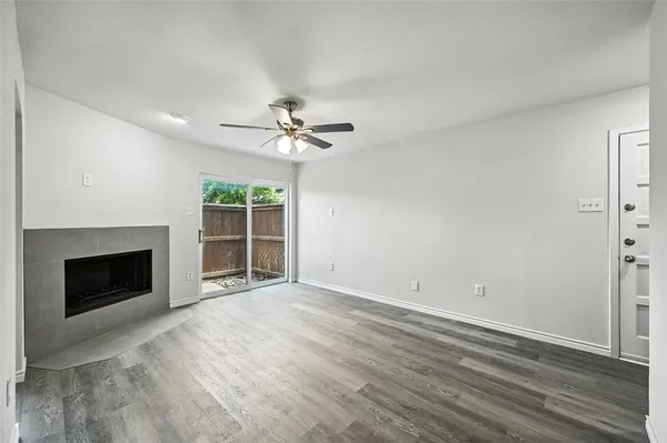 a view of an empty room with wooden floor fireplace and a window